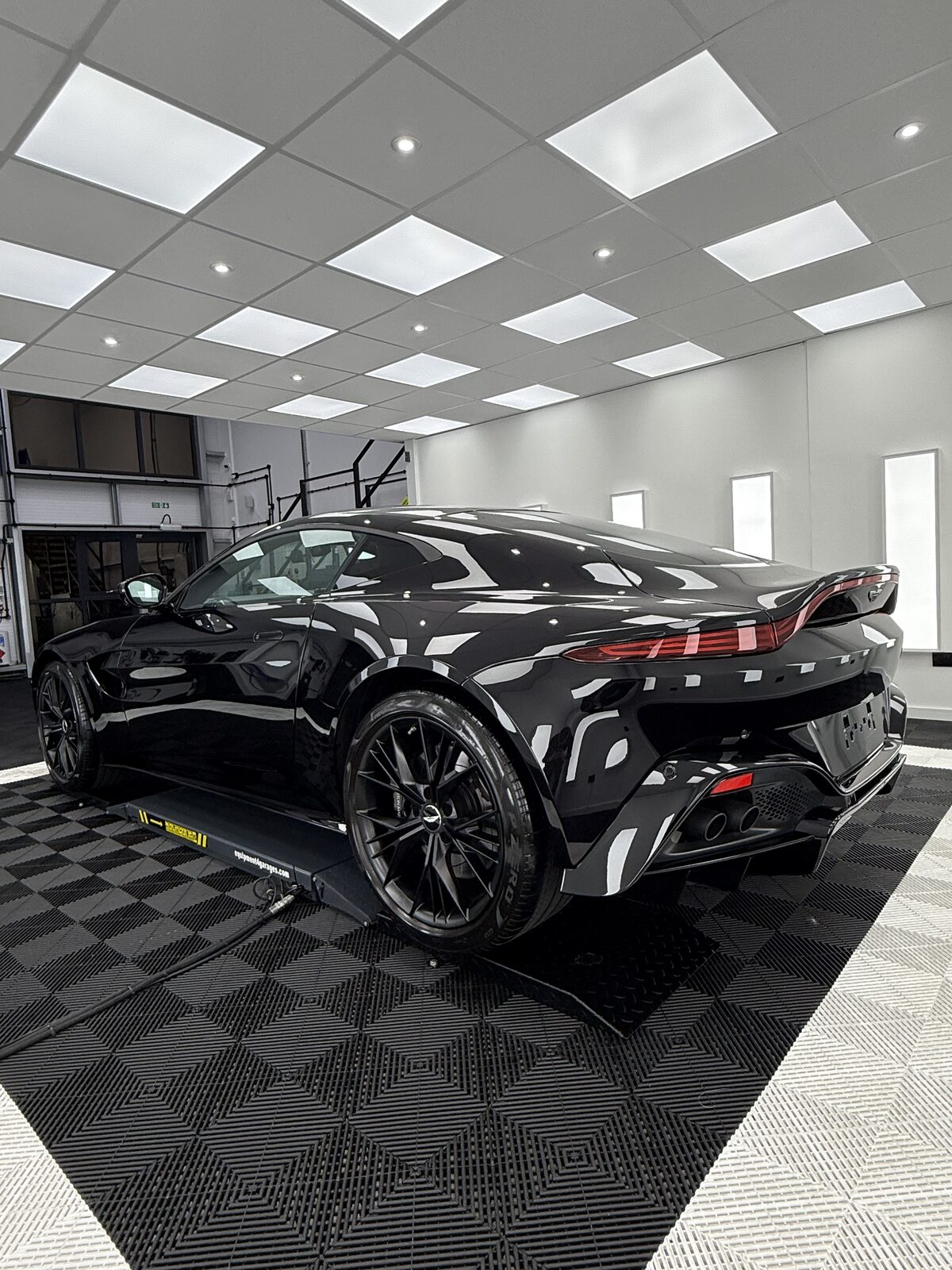 Gloss black Aston Martin Vantage rear three quarter view in the Elevate Detailing UK studio bay