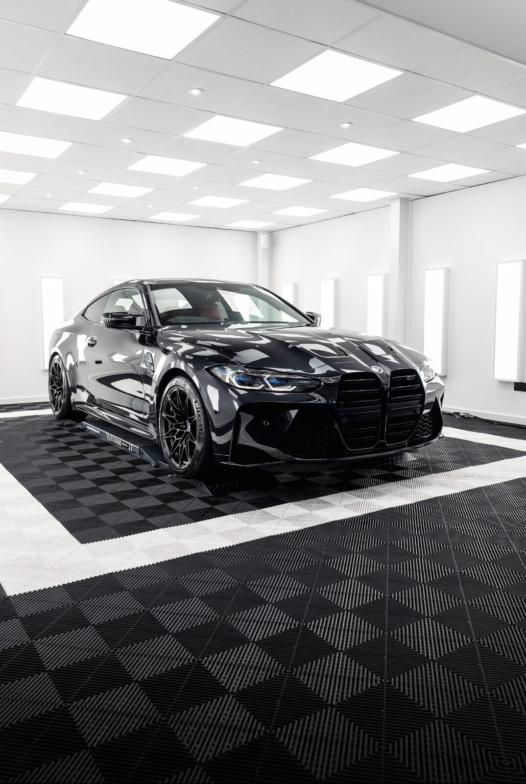 Gloss black BMW M4 coupe front three quarter view in the Elevate Detailing UK studio in Exeter