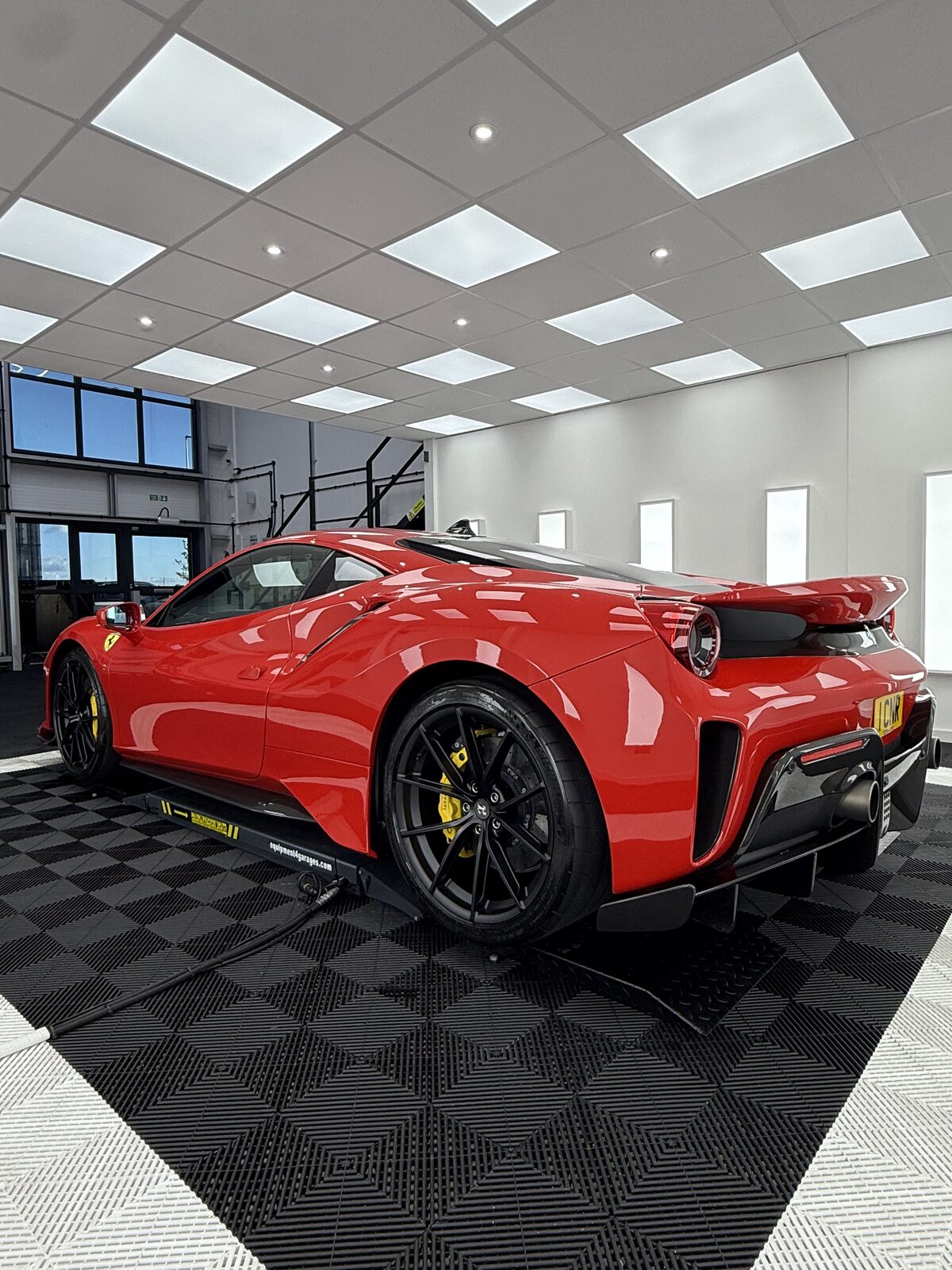 Red Ferrari 488 Pista with a mirror-gloss finish on a lift inside the Elevate Detailing UK studio in Exeter