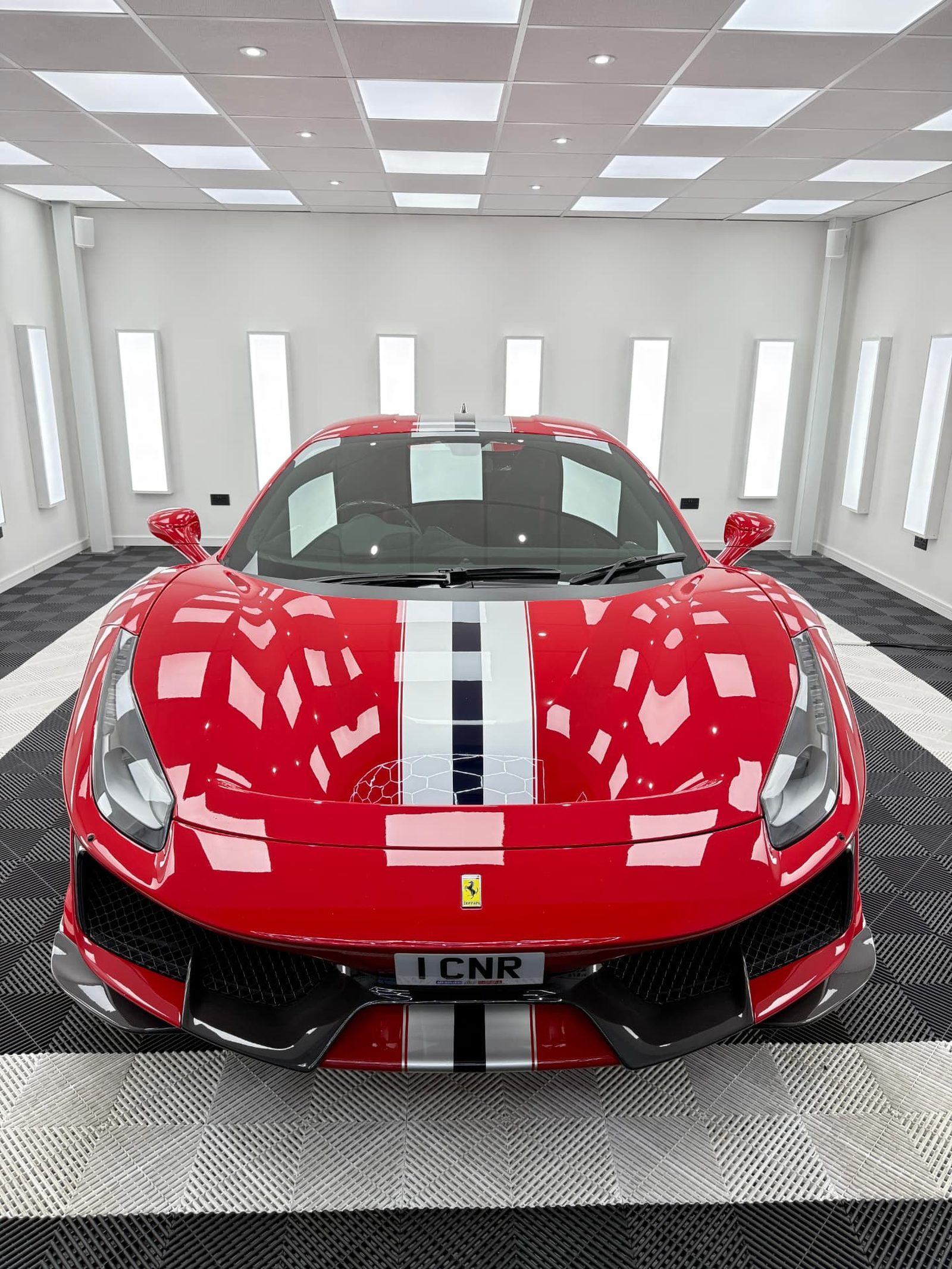 Red Ferrari 488 Pista with racing stripes front-on in the Elevate Detailing UK studio in Exeter